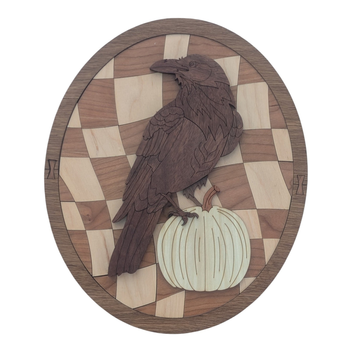 Wood marquetry oval of a raven perched on a pale pumpkin, in front of a warped light-and-dark checkerboard in a walnut frame.