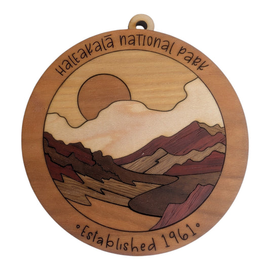 “Round Haleakalā National Park wood ornament with a sun, cream clouds, burgundy crater ridges, and ‘Established 1961’ engraving.”
